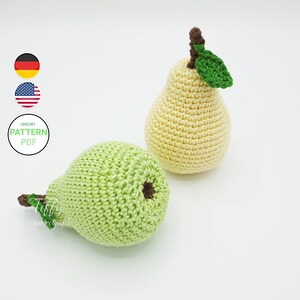 Puede incluir: Dos peras de crochet, una verde y una amarilla, sobre un fondo blanco. La pera verde tiene un tallo marrón y una pequeña hoja verde. La pera amarilla tiene un tallo marrón y una hoja verde.
