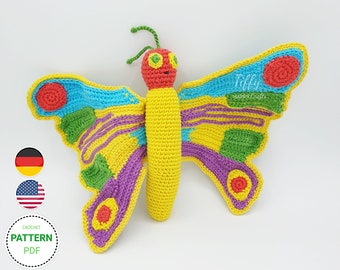 May include: A crocheted butterfly toy with yellow, red, green, blue, and purple accents. The butterfly has a long body and large wings with a circular pattern. The toy is made with yarn and has a whimsical design.