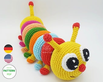 May include: A colorful crocheted caterpillar toy with a yellow head, black eyes, and a red nose. The caterpillar's body is made of multiple crocheted rings in different colors, including red, orange, yellow, green, blue, and pink.