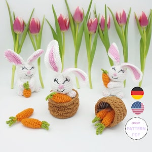 Könnte beinhalten: Häkelanleitung PDF zum Herstellen eines weißen Hasen mit rosa Ohren, der eine Karotte hält. Der Hase sitzt in einem braunen Korb mit Karotten. Das Bild zeigt auch einen Hintergrund mit rosa Tulpen.