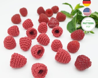 Könnte beinhalten: Eine Sammlung gehäkelter roter Himbeeren, ein beliebtes Bastelprojekt. Die gehäkelten Himbeeren sind auf einer weißen Oberfläche verstreut.