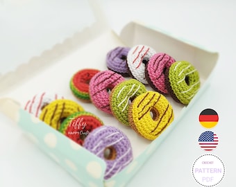 May include: A box of colorful crocheted donuts with white frosting and sprinkles. The donuts are in a white and blue polka dot box. The text "Tiffy Happy Crafts" is visible on the box. The image also includes the text "CROCHET PATTERN PDF" and flags for Germany and the United States.