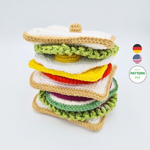 Puede incluir: Patrón de crochet para un juguete amigurumi de sándwich de varios pisos. El patrón incluye instrucciones para hacer el pan, la lechuga, el tomate, el queso y el huevo. El patrón está disponible en formato PDF y está escrito en inglés y alemán.