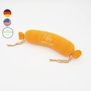 May include: A crocheted orange sausage plush toy with a brown string attached to each end. The toy is labeled "Tiffy Happy Crafts".