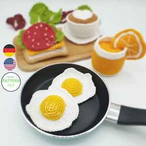 Op de afbeelding: Haakpatroon voor een ontbijt speelset. De set bevat een gebakken ei, een glas sinaasappelsap, een kop koffie en een sandwich. Het patroon is beschikbaar als PDF-download. Tiffy Happy Crafts.
