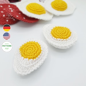 May include: Crocheted fried egg appliques with white egg whites and yellow yolks. The image also shows a red crocheted strawberry and a graphic that says "Crochet Pattern PDF".