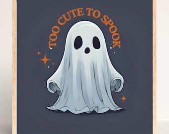 May include: A framed print with a cartoon ghost and the text "TOO CUTE TO SPOOK" in orange. The ghost is white with a light blue shadow, set against a dark blue background. Orange stars accent the design. The frame is made of light wood.