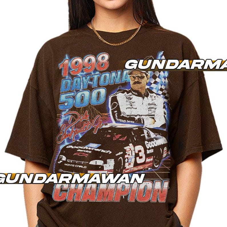 Peut inclure: Un t-shirt &agrave; manches courtes marron fonc&eacute; avec une impression graphique du Daytona 500 de 1998, Dale Earnhardt et sa voiture de course num&eacute;ro 3. Le design comprend des &eacute;clairs bleus, un drapeau &agrave; damier et le texte GUNDARMAWAN CHAMPION.
