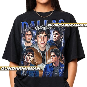 May include: Black t-shirt with a collage of images of a man and the text "DALLAS Winston" in blue and white. The design includes lightning bolt graphics. The shirt has a vintage style.