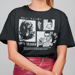 May include: Black t-shirt featuring a graphic design with the text "EREN YEAGER" and Japanese text. The design includes multiple panels with illustrations of a male character. The shirt is a crew neck style.