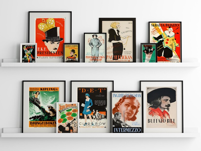 May include: A white shelf with black framed vintage movie posters. The posters feature images of actors and actresses, including Charlie Chaplin, Ingrid Bergman, and Buffalo Bill. The posters are in various colours and styles, and some have text in different languages.