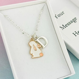 May include: A silver necklace with a white bunny charm and a silver letter D charm. The necklace is in a white box with the text "Your Message Here".