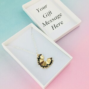 May include: A gold pencil sharpener necklace in a white gift box. The box has the text "Your Gift Message Here" on the lid.