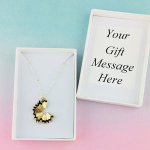 May include: A gold pencil sharpener charm necklace in a white gift box. The box has a white card with the text "Your Gift Message Here".