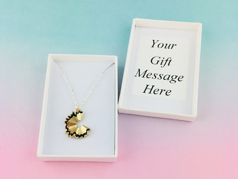 May include: A silver chain necklace with a gold pencil shaving pendant in a white gift box. The box has a white card inside with the text "Your Gift Message Here".