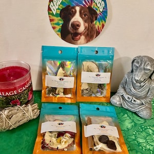 May include: A selection of products featuring four small pouches filled with dried herbs and flowers, a candle, a sage bundle, and a sign with a dog and the text "Bear's Best Wishes." A silver dog statue is also visible.