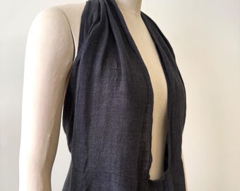 May include: A dark gray halter dress with a deep V-neck and open back. The dress is made of a soft, flowing fabric and drapes elegantly. The dress is displayed on a mannequin.