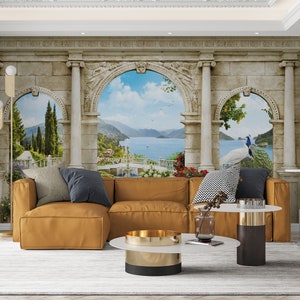 May include: A living room scene featuring a mustard-colored sectional sofa, a white and gold coffee table, and a rug. The focal point is a large mural depicting an Italianate landscape with arches, columns, and a peacock.