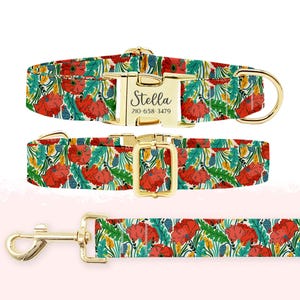 May include: A dog collar and leash set featuring a vibrant floral pattern with red poppies, green leaves, and yellow accents. The collar has a gold-colored buckle with the name "Stella" and a phone number. The leash has a matching floral design and gold-colored hardware.