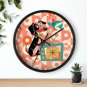 Può includere: Un orologio da parete rotondo con cornice nera. Il quadrante presenta un cane dei cartoni animati che guarda la TV. Il cane è bianco e nero con pois rossi. Lo sfondo ha un motivo geometrico pesca, crema e arancione. Lancette nere.