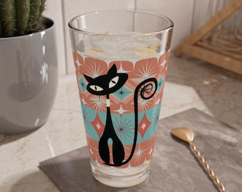 Puede incluir: Un vaso de vidrio transparente con un diseño retro que presenta un gato negro con la cola enroscada. El gato está sobre un fondo de formas geométricas rosas, azules y blancas.
