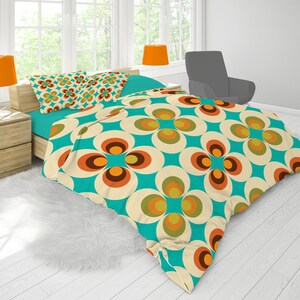 Puede incluir: Una funda nórdica turquesa y crema con un patrón retro de círculos superpuestos en tonos naranja, marrón y verde. La funda nórdica está en una cama con dos fundas de almohada a juego.