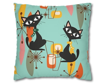 May include: A turquoise blue throw pillow with a repeating pattern of black cats, yellow stars, and abstract shapes in orange, yellow, and green.