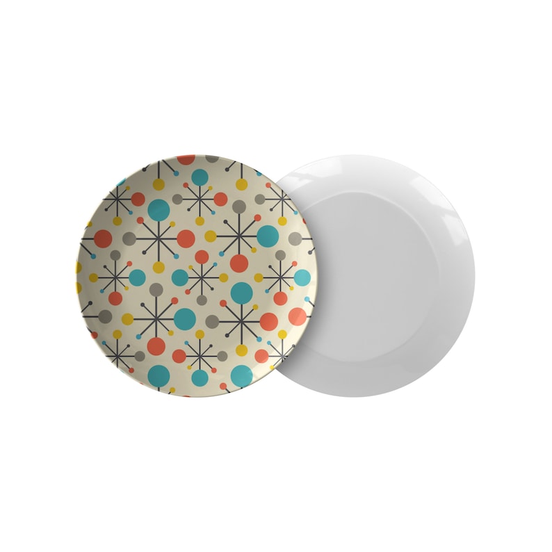 May include: A set of two ceramic plates, one with a white background and the other with a retro-style pattern of colourful circles and stars.