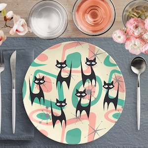 Könnte beinhalten: Ein weißer Keramik-Dinnerteller mit einem Retro-Design mit schwarzen Katzen und abstrakten Formen in Rosa-, Grün- und Weißtönen.