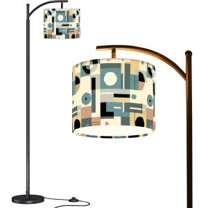 May include: A modern floor lamp with a black metal frame and a curved arm supporting a cylindrical lampshade. The lampshade features a geometric pattern in teal, beige, black, and pink. The lamp has a round base and a foot switch.