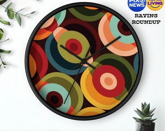 May include: A black framed clock with a colourful geometric pattern of overlapping circles in shades of red, orange, yellow, green, blue, and brown. The clock face is black with white hands.