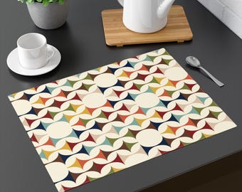 Può includere: Un tovaglietta con un motivo geometrico colorato su sfondo crema. Il motivo presenta un design ripetitivo di cerchi e triangoli sovrapposti in tonalità di rosso, blu, verde, giallo e marrone.