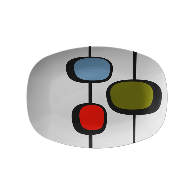 May include: A white oval serving platter with a mid-century modern design. The platter features three abstract shapes in red, blue, and green, connected by black lines.