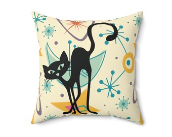 May include: Square throw pillow with a retro design featuring a black cat silhouette. The pillow has a cream background with teal, yellow, and purple geometric shapes and starburst patterns. A decorative accent for a sofa or bed.