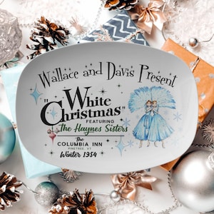 May include: White oval serving platter with a vintage design featuring a Christmas scene. The text reads "Wallace and Davis Present "White Christmas" Featuring The Haynes Sisters The Columbia Inn Pinetree, VT Winter 1954".