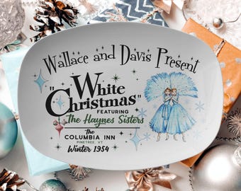 May include: White oval serving platter with a vintage design featuring a Christmas scene. The text reads "Wallace and Davis Present "White Christmas" Featuring The Haynes Sisters The Columbia Inn Pinetree, VT Winter 1954".