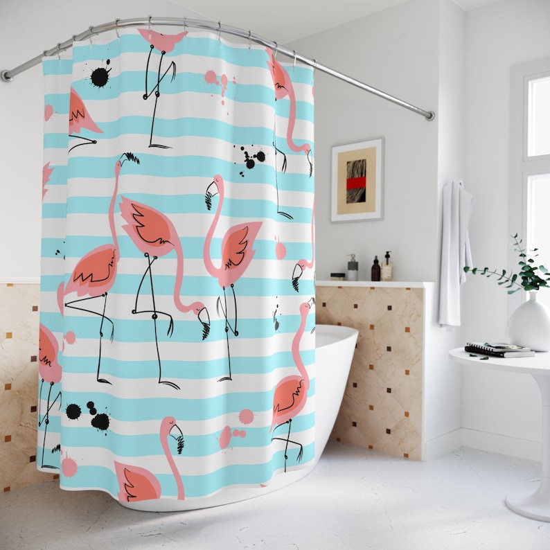 Pu&ograve; includere: Una tenda da doccia a strisce blu e bianche con un motivo di fenicotteri rosa. La tenda da doccia ha schizzi di vernice nera ed &egrave; appesa in un bagno.