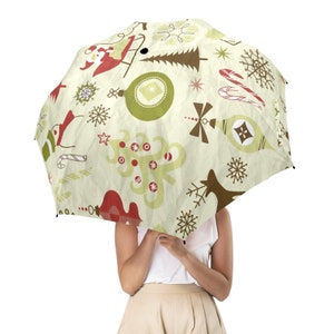 May include: A white umbrella with a Christmas-themed design. The umbrella features a pattern of red and green ornaments, candy canes, snowflakes, and Christmas trees on a cream background.