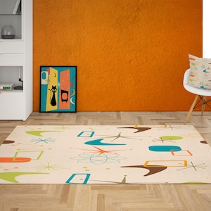 May include: A mid-century modern style rug with a cream background and colorful geometric shapes in orange, green, brown, and blue. A framed art print with a black cat and a white chair with a patterned pillow are also visible.