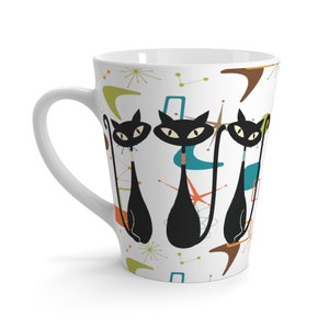 May include: White ceramic latte mug with a retro design featuring three black cats with long tails and a white background with colorful abstract shapes.