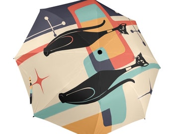 May include: A retro-style umbrella with a colourful abstract design featuring two black cats. The umbrella has a cream background with orange, blue, and red geometric shapes.