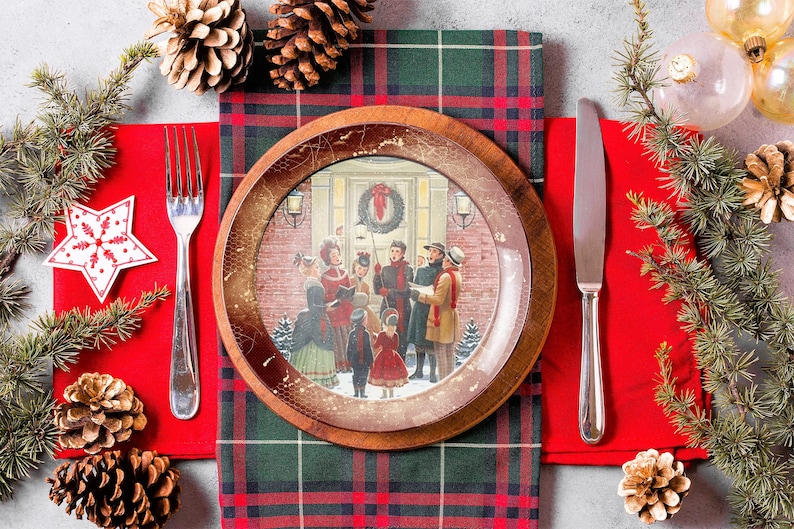 May include: A Christmas-themed dinner table setting with a red and green plaid tablecloth, a wooden plate with a vintage illustration of carolers, a red napkin, a silver fork and knife, and pine branches with pine cones.