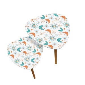 May include: A set of two white nesting tables with a mid-century modern atomic pattern in shades of teal, orange, and white.