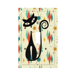 May include: A decorative light switch cover featuring a black cat silhouette with a curled tail. The cat is set against a cream background with a pattern of colorful diamonds and starbursts. The switch opening is white.