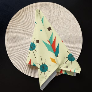May include: A yellow, white, blue, red, and orange geometric patterned cloth napkin with a mid-century modern design.