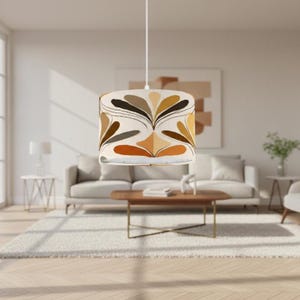 May include: A pendant light with a cylindrical lampshade. The lampshade has a symmetrical floral pattern in brown, tan, and orange on a cream backdrop. The light is suspended from a white cord.