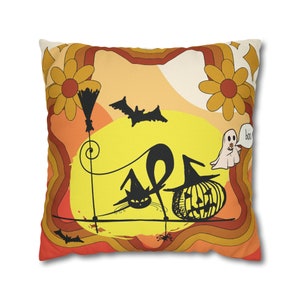 May include: A square cushion with a retro-style Halloween design. The cushion features a black cat, a pumpkin, a ghost, and bats on a yellow background with orange and brown accents. The text "boo" is written on the cushion.
