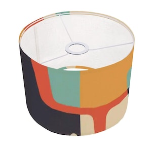 Puede incluir: Una pantalla de lámpara cilíndrica con un patrón geométrico en tonos naranja, amarillo, verde azulado, rojo y negro.
