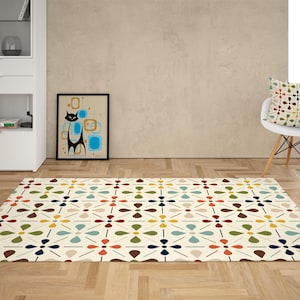 May include: A cream-colored area rug with a repeating floral pattern in red, blue, green, and yellow. A framed art print of a black cat and a white chair with a patterned pillow are also in the room.