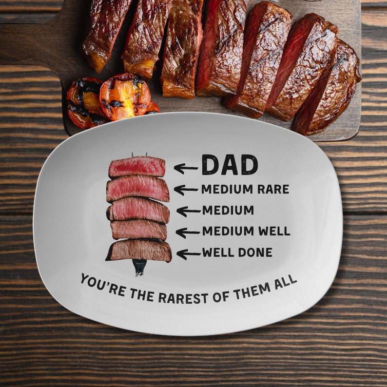 May include: White oval ceramic serving platter with a graphic of a steak cut into different levels of doneness. The text reads "DAD" and "You're the rarest of them all".